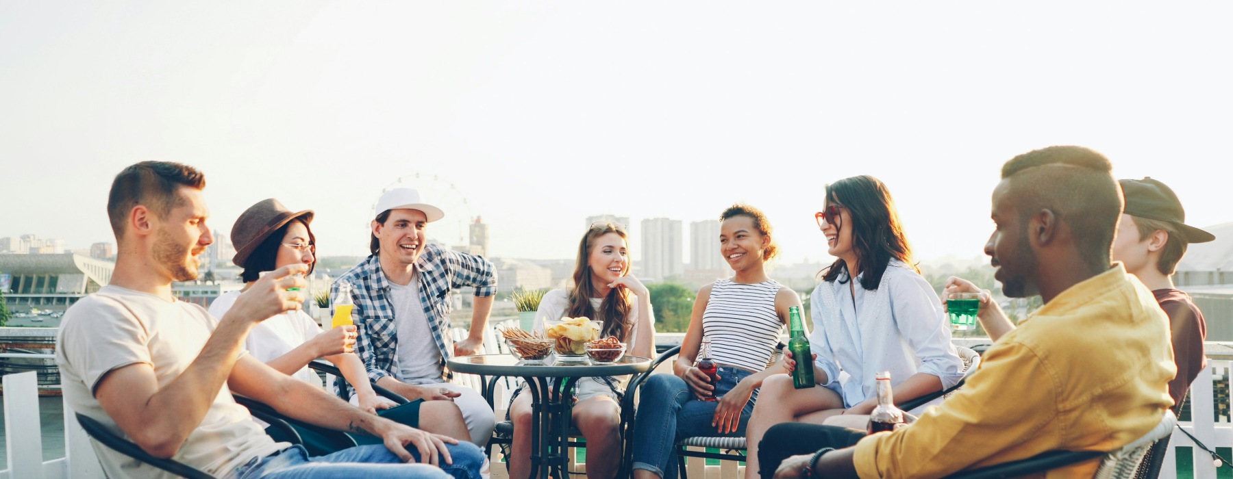 friends sitting outdoors around a table and eating/drinking